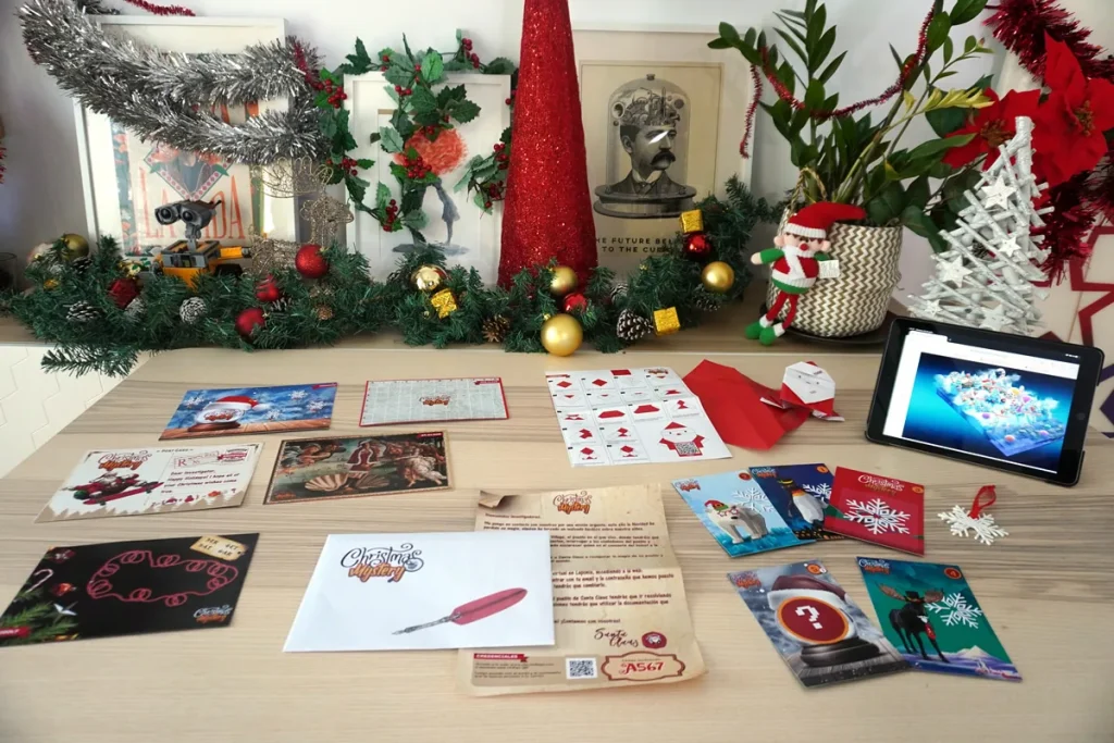 Tarjetas, sobres y tablet de un escape room navideño sobre la mesa, entre las actividades para fiestas de Navidad de empresa