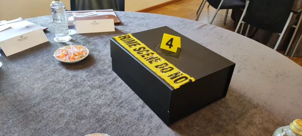 Beneficios escape room empresas: caja de un juego de investigación con cinta de escena del crimen sobre la mesa de una sala de reuniones