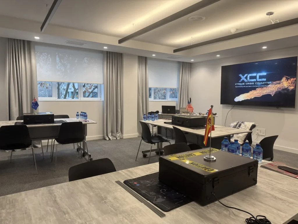 Actividades para kick off de empresa: sala de reuniones con una mesa por equipo y una pantalla preparada para un reto de crisis