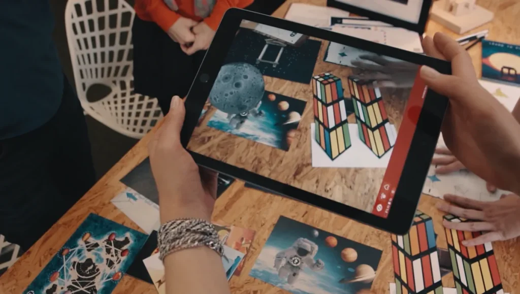 Manos sujetando una tableta con un reto de realidad aumentada durante un escape room para empresas en Barcelona
