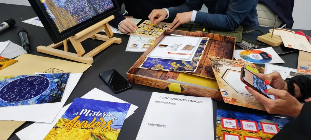 Mesa de El Misterio de Van Gogh en un escape room para empresas en Barcelona, con cuadros, cartas y un móvil con realidad aumentada