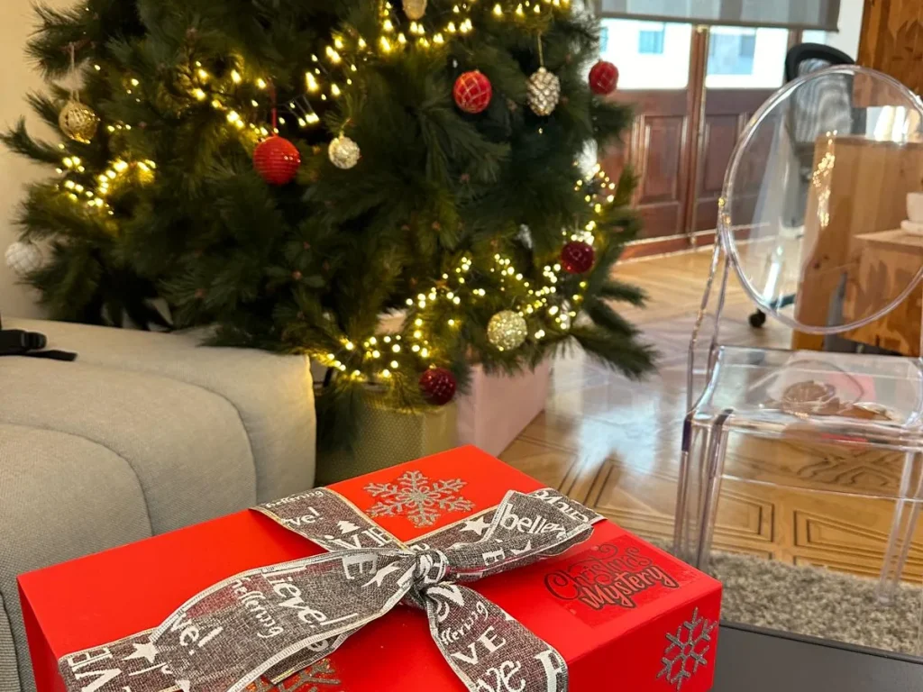 Juegos para cenas de empresa: una caja de juego con lazo junto al árbol de Navidad del restaurante