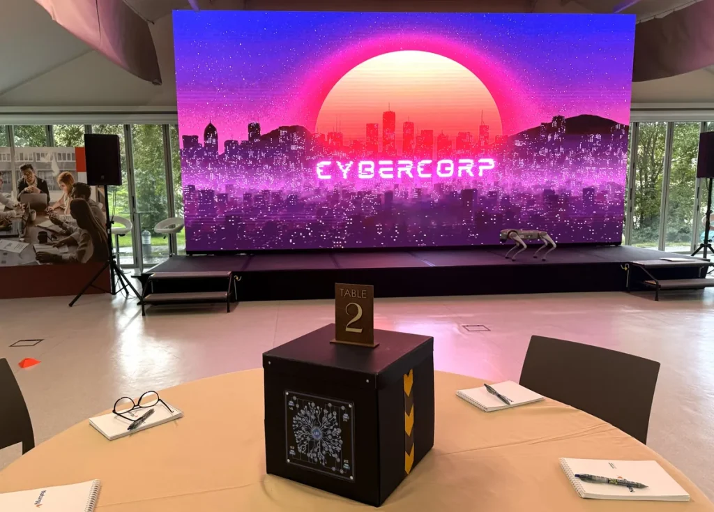 Juegos para trabajadores: evento con Cybercorp, escenario con pantalla y una caja de juego en cada mesa