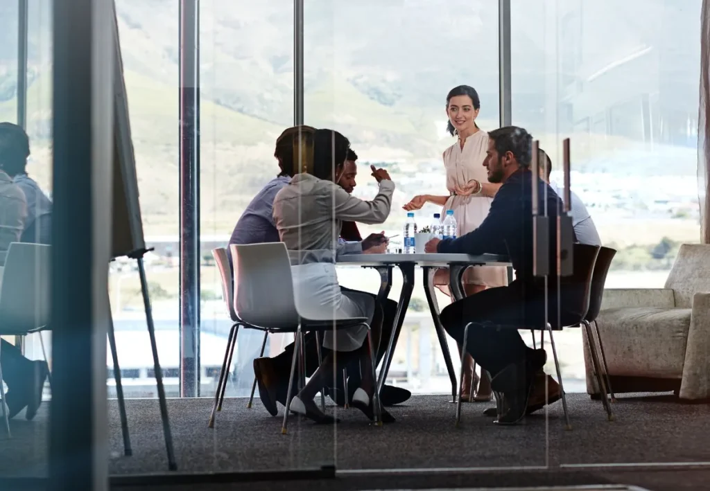 Team building de estrategia: un equipo reunido alrededor de una mesa en una sala de reuniones acristalada