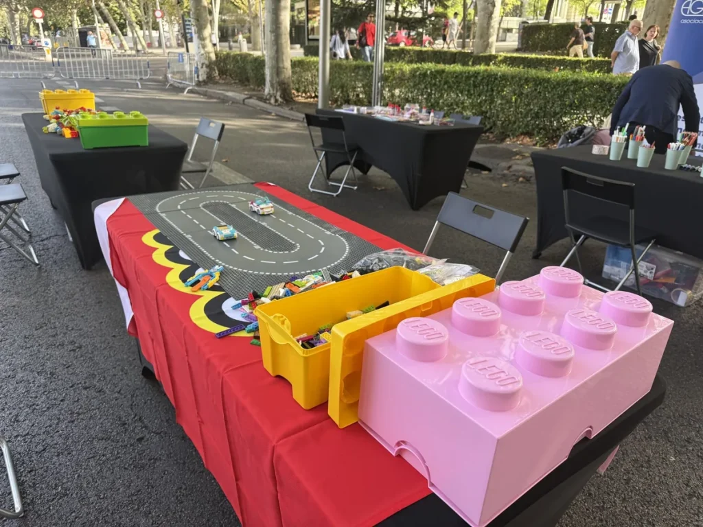 Team building en Madrid: mesas con material de pruebas por equipos al aire libre, en un paseo arbolado