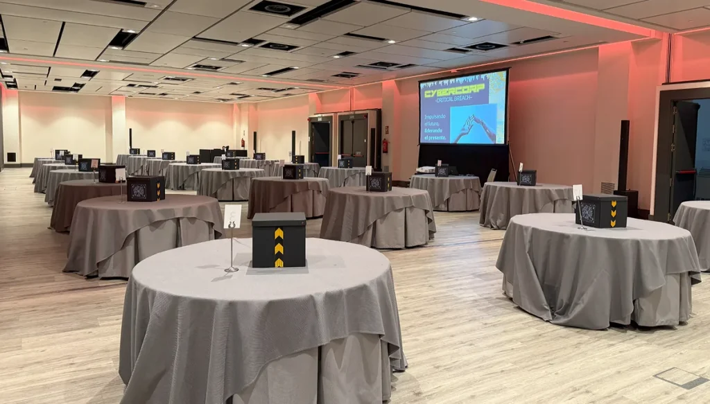 Team building para empresas: salón de hotel con mesas redondas y una caja de juego en cada mesa antes de empezar